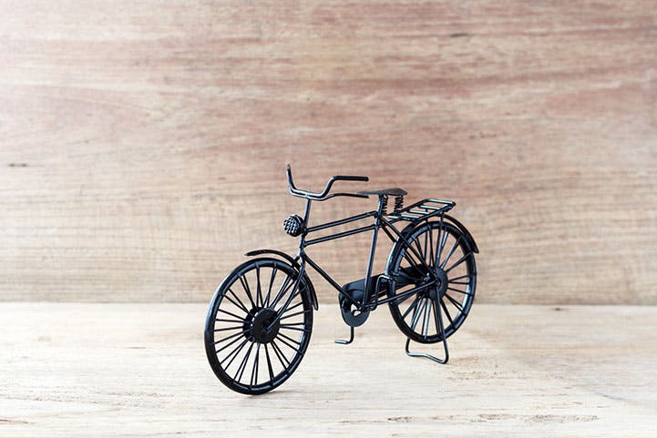 Vintage model black bicycle on old wooden table.